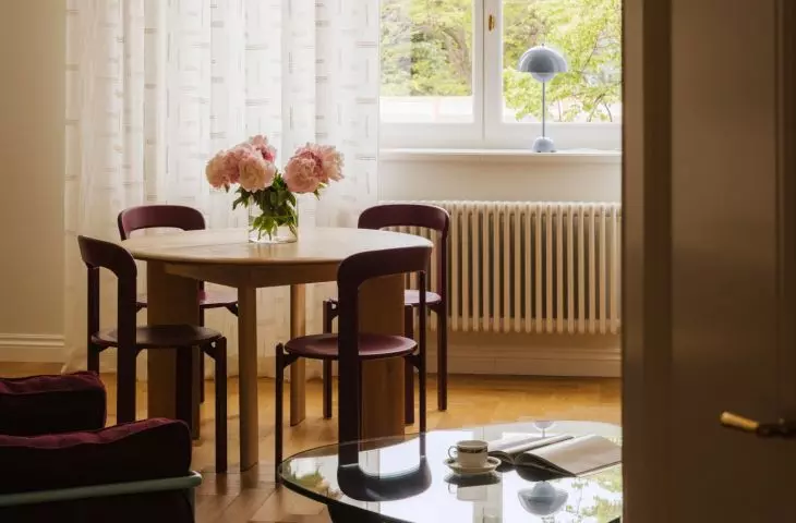 Large windows, soft curtains, and a view of the greenery keep the living area bright and very cozy