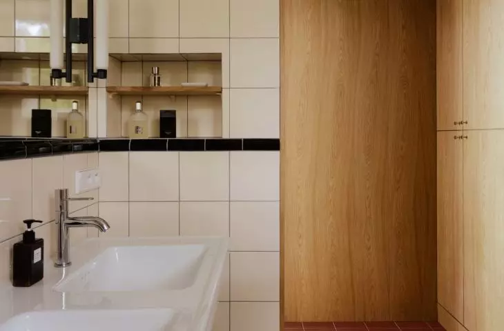 The bathroom combines functionality with coziness. The wooden cabinetry adds warmth to the space and flows seamlessly into the rest of the apartment.