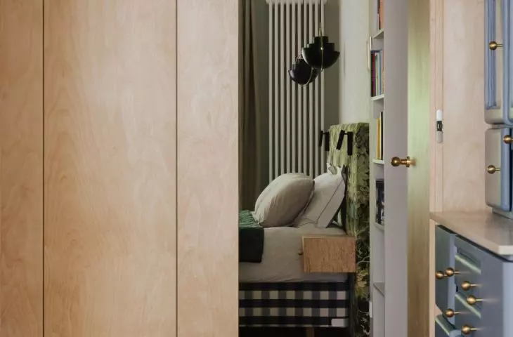The entrance to the bedroom is concealed within the wooden built-in cabinetry. This helps keep the private area of the house more intimate and peaceful