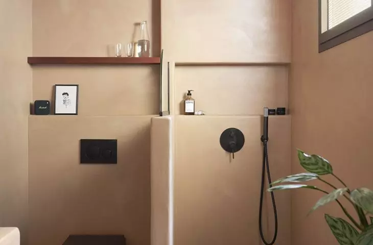The second bathroom features earthy tones, seamless surfaces, and a more subdued atmosphere