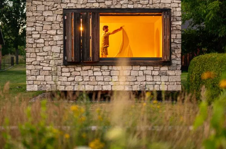 The stone gives the building a simple, austere form, while the windows open it up to the garden