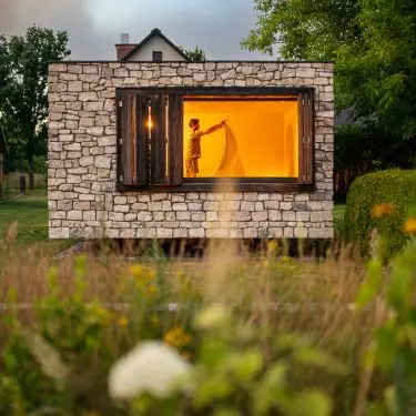 The stone gives the building a simple, austere form, while the windows open it up to the garden