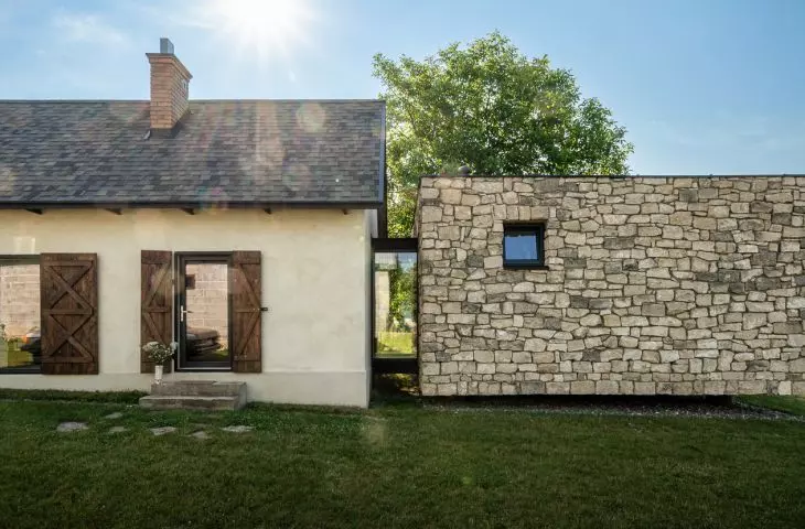 The former stable and the new stone structure come together in a single frame: plaster, wood, and stone create a serene blend of old and new