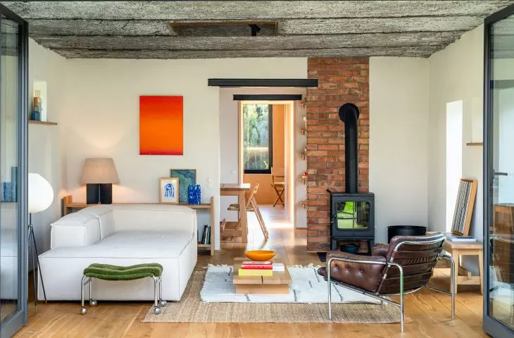 The brick walls and exposed ceiling give the living room a raw, industrial feel, while the artwork, records, and plush furniture create a cozy, personal atmosphere