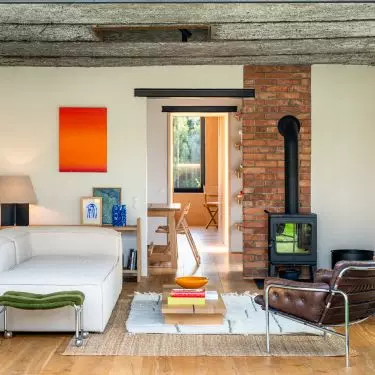 The brick walls and exposed ceiling give the living room a raw, industrial feel, while the artwork, records, and plush furniture create a cozy, personal atmosphere