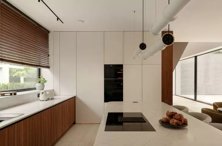 The kitchen embraces elegant minimalism: light-colored cabinetry, wooden cabinet fronts, and a stone countertop
