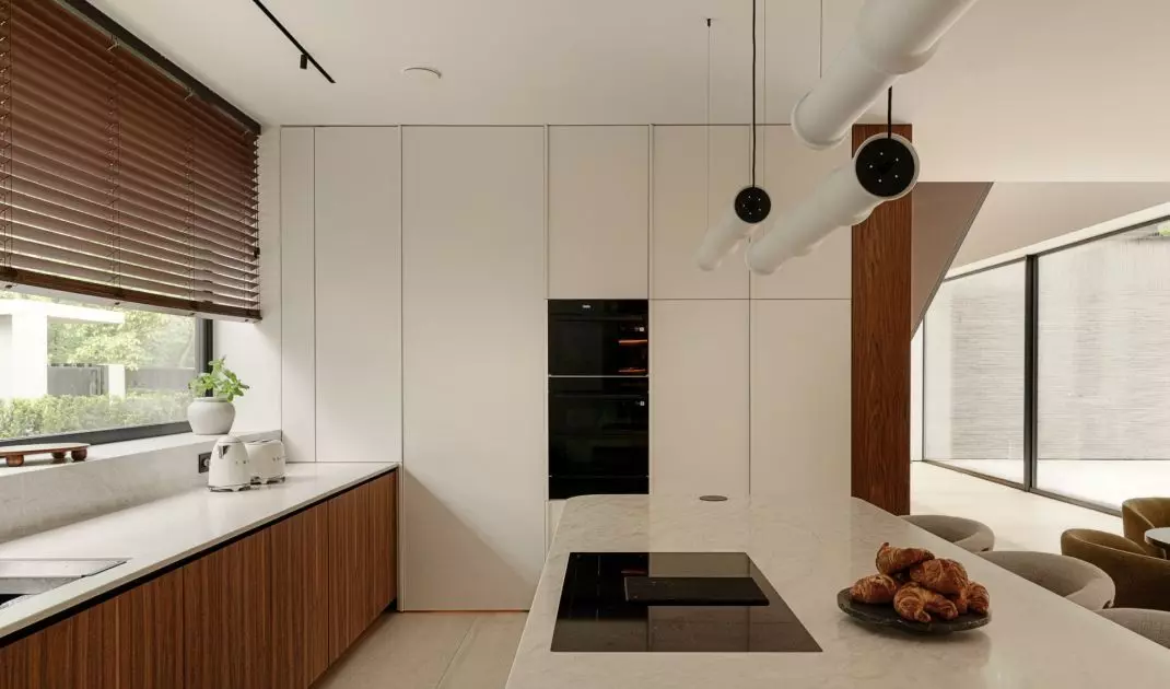 The kitchen embraces elegant minimalism: light-colored cabinetry, wooden cabinet fronts, and a stone countertop