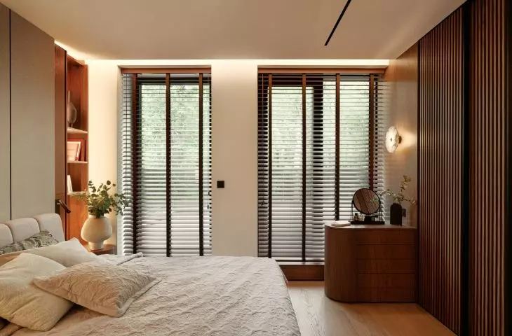 The bedroom was designed as a quiet, cozy space featuring an upholstered bed, wood, and soft lighting