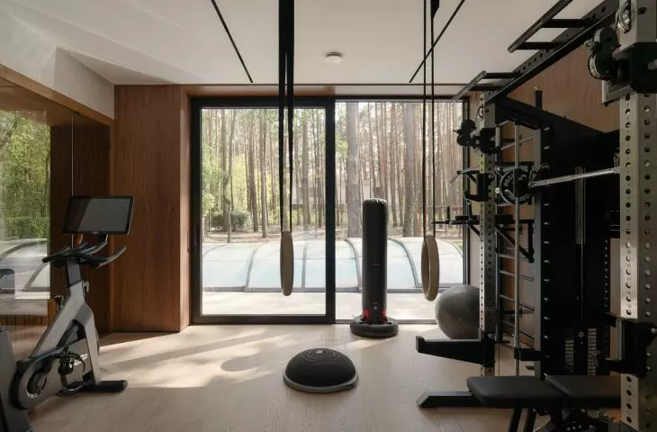 The home gym overlooks a pine forest, allowing workouts to remain part of daily contact with nature