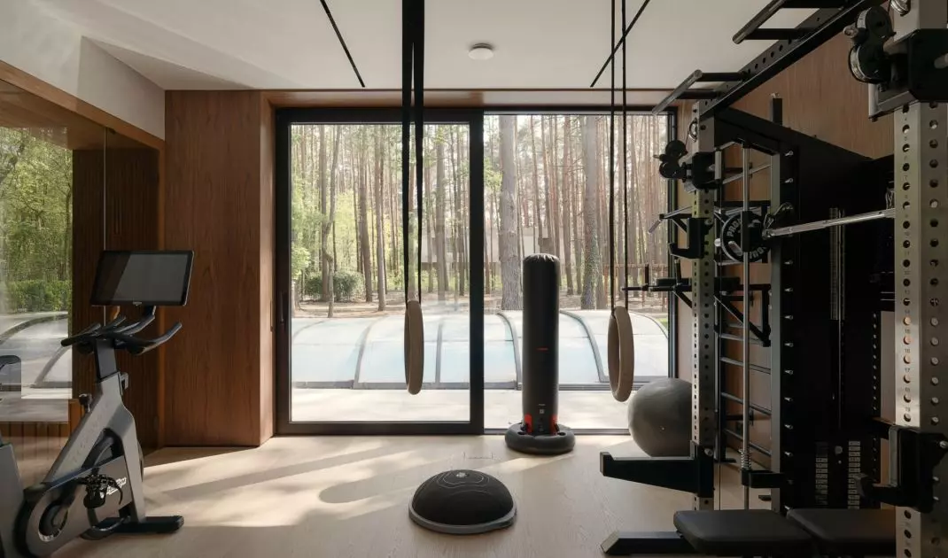 The home gym overlooks a pine forest, allowing workouts to remain part of daily contact with nature