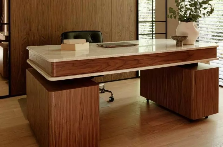 The office features an elegant combination of wood and stone, and the large windows bring light and greenery into the space