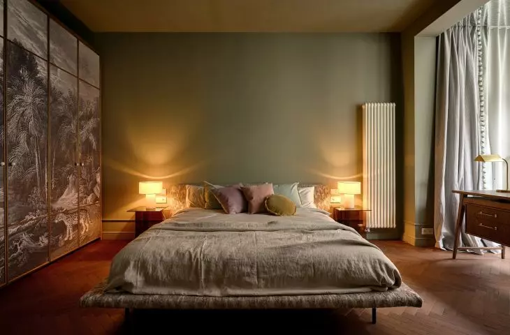 The bedroom is the coziest part of the apartment. The green walls, soft fabrics, and decorative wardrobe bring a sense of calm to the space, without sacrificing striking details.