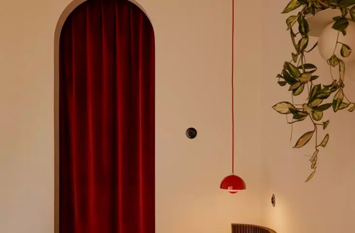 The burgundy curtain and the rounded arch give the bedroom a soft, intimate feel
