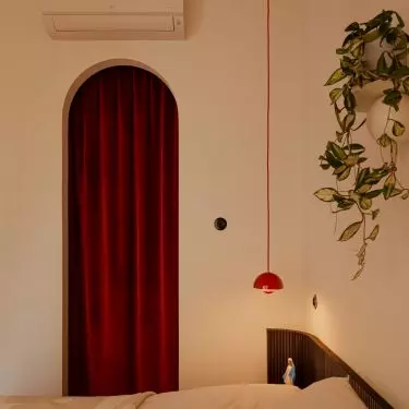 The burgundy curtain and the rounded arch give the bedroom a soft, intimate feel