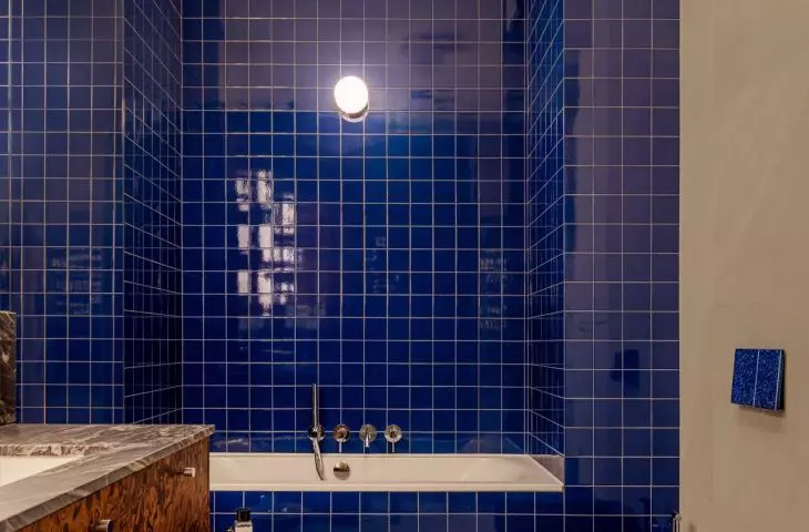 The vivid blue in the larger bathroom creates a striking contrast to the warm browns found throughout the apartment