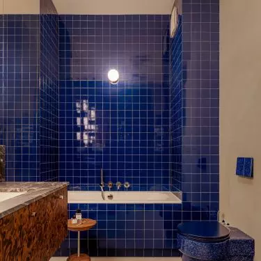 The vivid blue in the larger bathroom creates a striking contrast to the warm browns found throughout the apartment