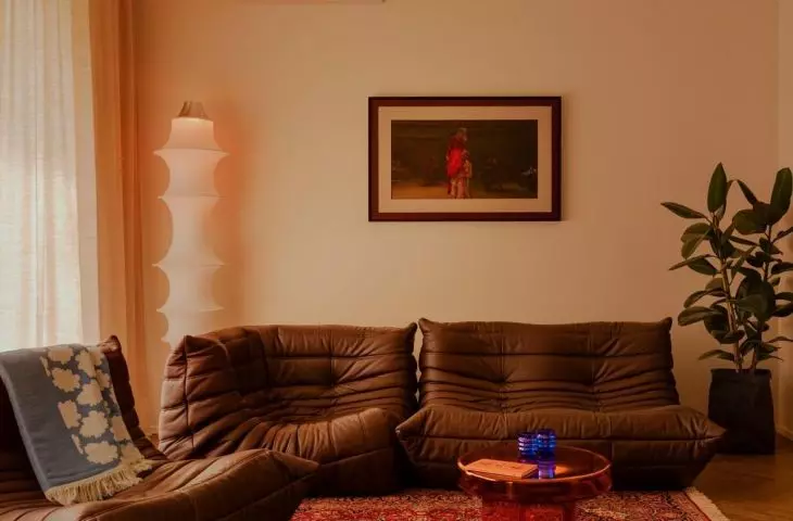 A living area with a Persian rug, chocolate-brown leather, and a see-through red coffee table