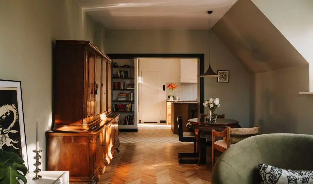 W salonie rodzinne meble i znaleziska vintage spotykają się z oliwkową zielenią i drewnianą podłogą ułożoną w jodełkę