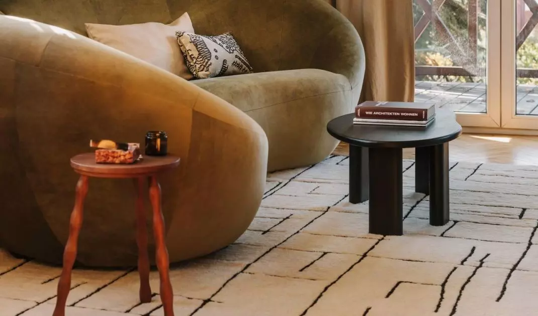Oliwkowa sofa o miękkiej, obłej formie przełamuje geometryczne skosy salonu