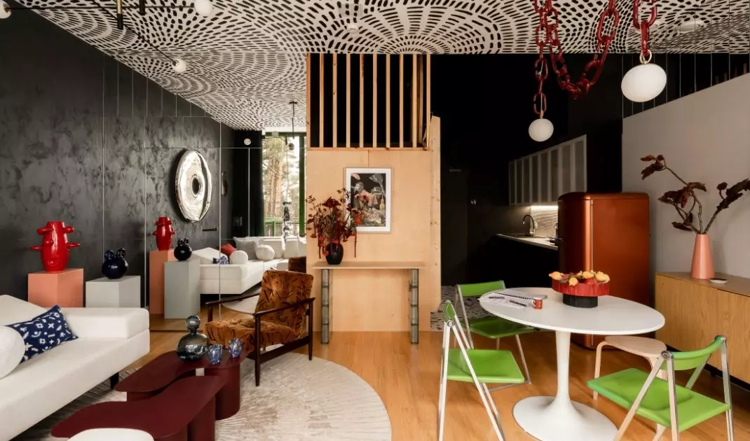 W salonie ciemną ścianę zestawiono z jasną sofą, drewnianą zabudową i designerskimi dodatkami. Centralnym akcentem jest lustro Rondo projektu Oskara Zięty