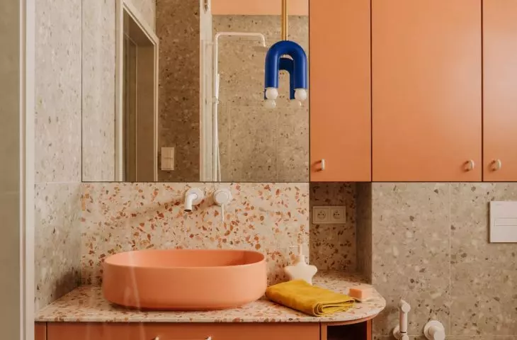 A vivid blue lamp adds a pop of color to the peach-colored bathroom