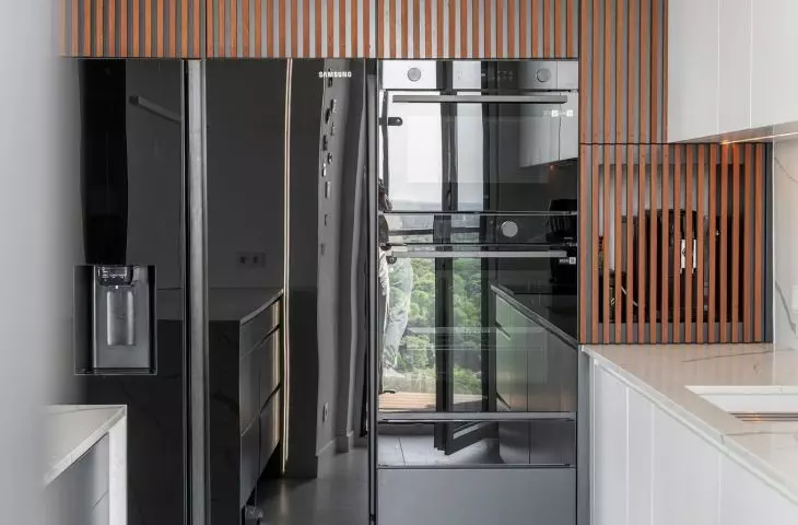 In the kitchen, the white cabinetry is accented by grooved fronts made of exotic wood