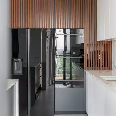 In the kitchen, the white cabinetry is accented by grooved fronts made of exotic wood