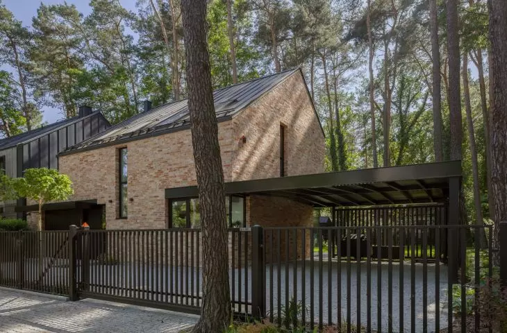 The asymmetrical roof and irregular brickwork echo Northern European interpretations of the barn-house