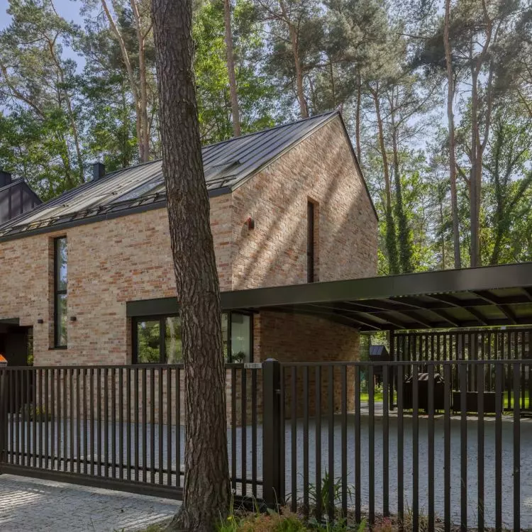 The asymmetrical roof and irregular brickwork echo Northern European interpretations of the barn-house