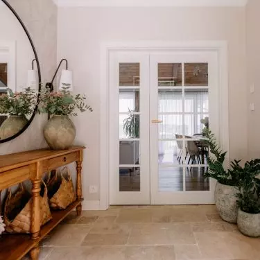 The bright entryway with travertine flooring sets the tone for the natural color palette of the entire interior