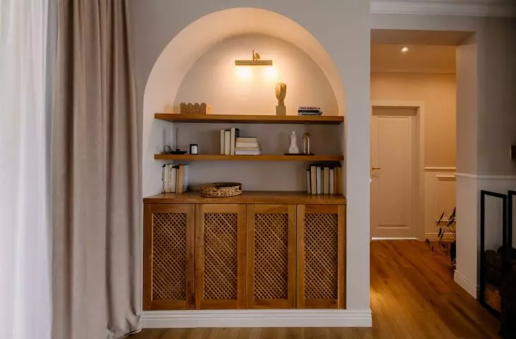 A wooden bookcase with rattan fronts was fitted into a rounded niche in the living room