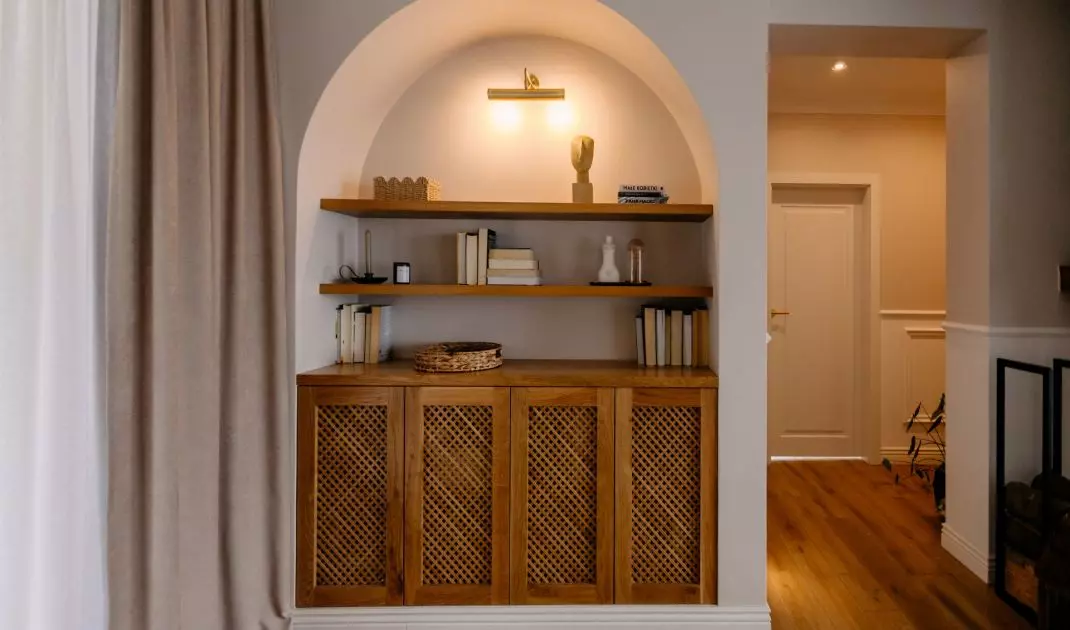 A wooden bookcase with rattan fronts was fitted into a rounded niche in the living room