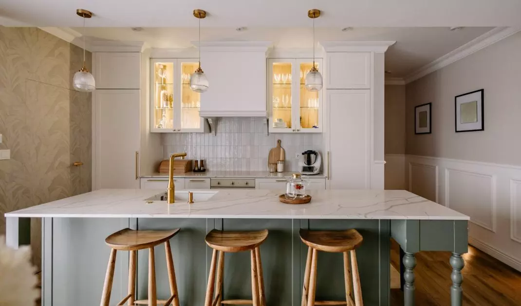 The olive-colored island breaks up the light, symmetrical kitchen cabinetry and serves as one of the interior’s strongest color accents