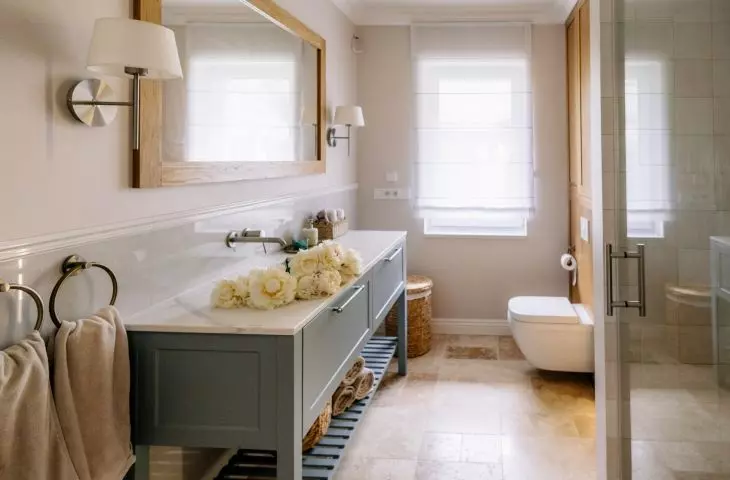 The master bathroom features a soothing color palette of dove blue, wood, and light-colored stone