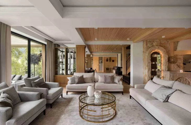 In the living area, light-colored furnishings are paired with wood and stone elements that serve as a reminder of the previous home
