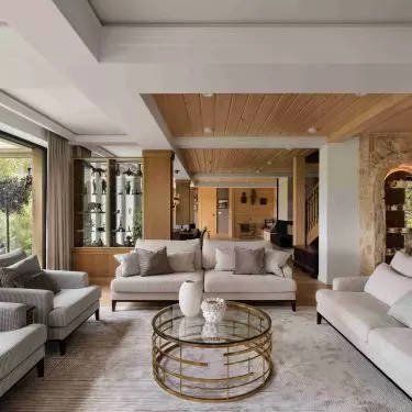 In the living area, light-colored furnishings are paired with wood and stone elements that serve as a reminder of the previous home