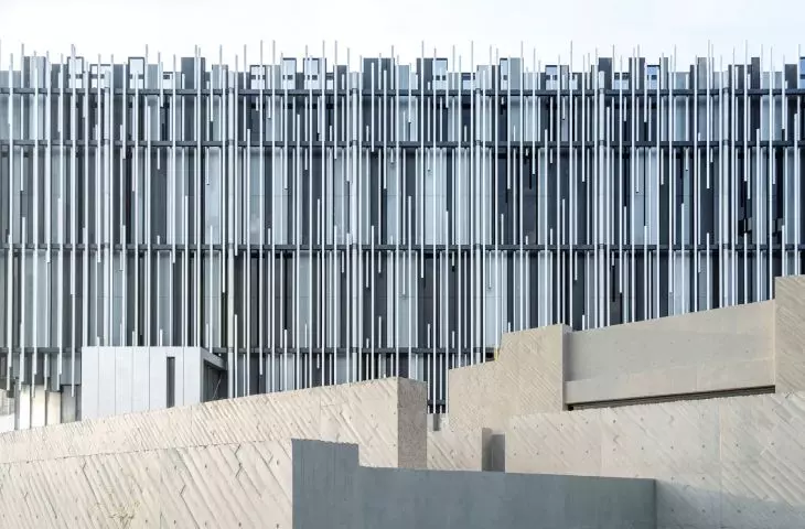 Warstwowa fasada muzeum została ukształtowana z pionowych aluminiowych profili o różnej długości i rytmie