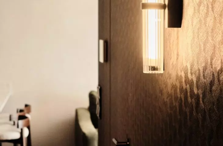 Embossed wallpaper covers the walls and hidden doors in the dark hallway