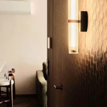 Embossed wallpaper covers the walls and hidden doors in the dark hallway