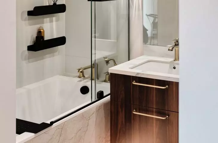 Wood veneer and brass accents add warmth to the bright bathroom