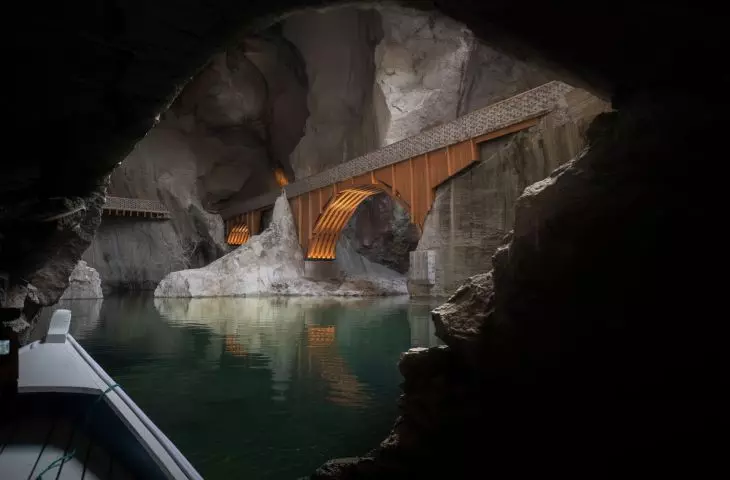 A wooden bridge spanning a turquoise reservoir in a former quarry