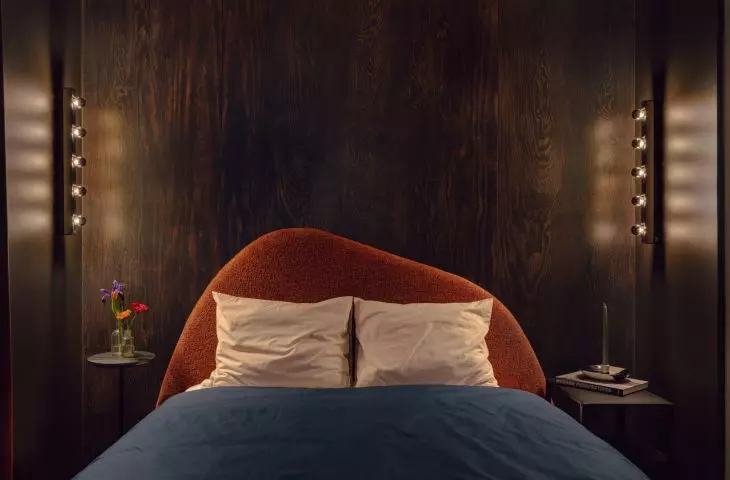 The organic shape of the upholstered bed softens the dark color scheme of the bedroom