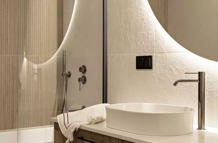 Grooved tiles and a wooden cabinet add warmth to the bright bathroom