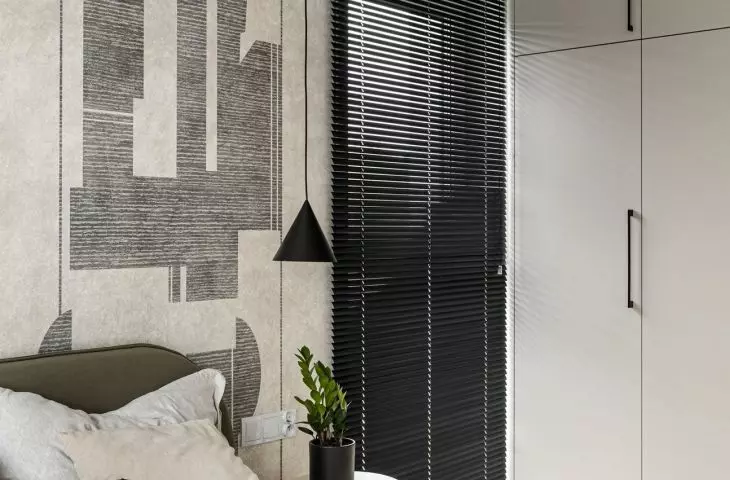 The graphic wallpaper serves as a backdrop for the sage-green headboard