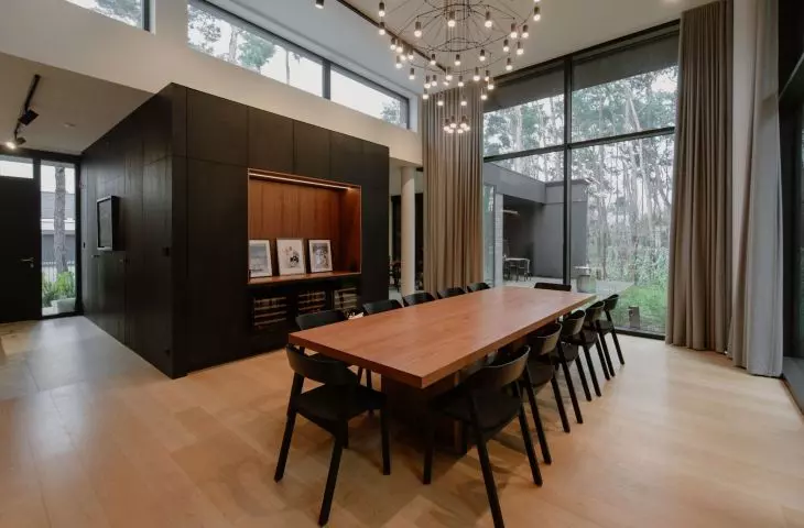 The black kitchen unit adjoins the dining room, which opens onto a pine forest
