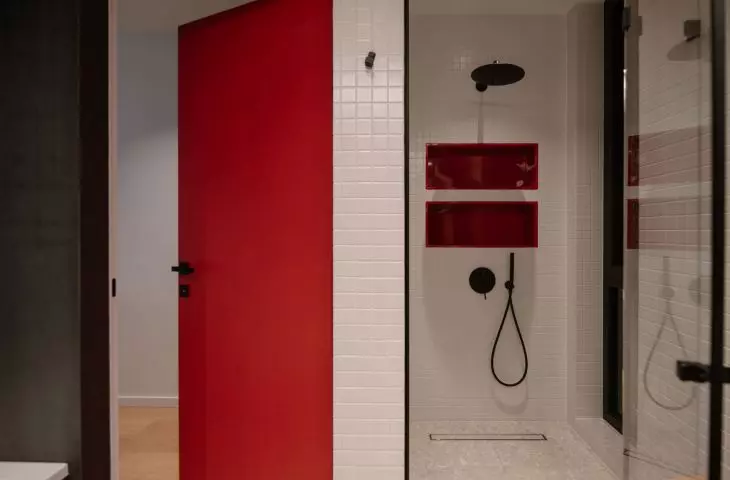 Red accents break up the bathroom's monochromatic color scheme
