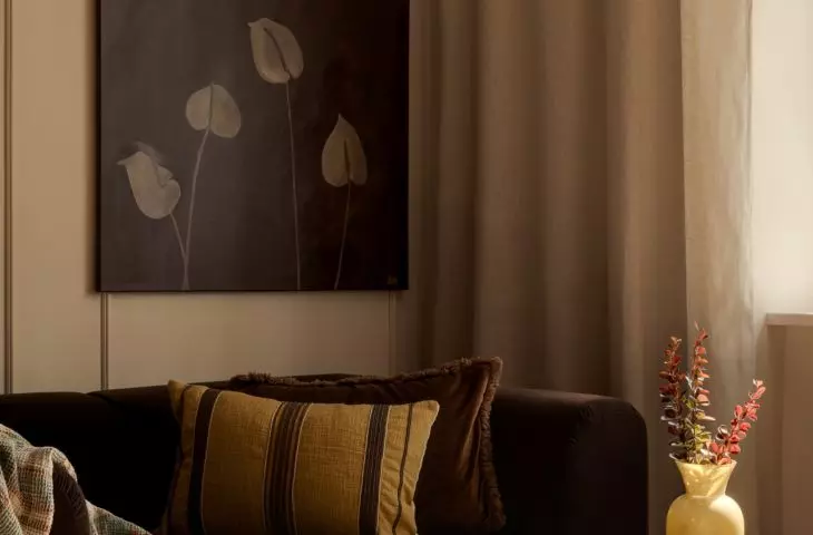 The living room's warm color scheme is complemented by a painting created by the future resident