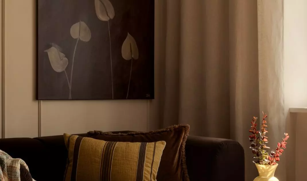 The living room's warm color scheme is complemented by a painting created by the future resident