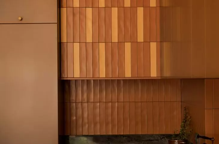 The yellow tiles break up the brick-red tones of the kitchen and complement the cabinet handles