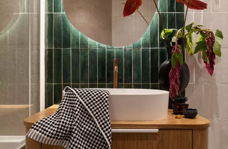 Dark green tiles and a lighted mirror give this small bathroom a distinctive character